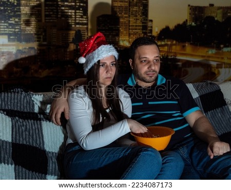 Adult girl and guy are watching TV, eating popcorn. Selective focus. Picture for website about family, leisure.