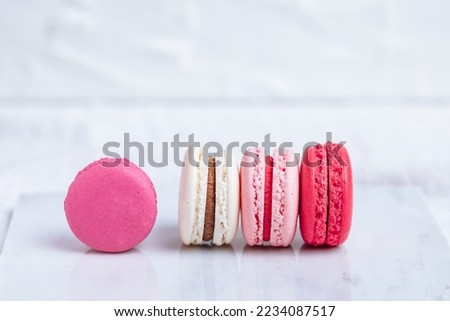 Close up of Macaroons in different colours on bright white background with subtle reflection on marble tray. Popular merengue dessert with filling inside.  Royalty-Free Stock Photo #2234087517