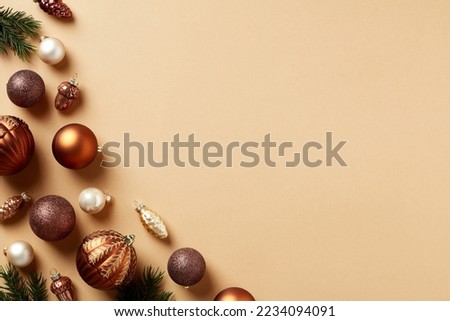 Elegant Christmas card. Flat lay bronze and brown color baubles, pine branches, cones decorations on beige background. Vintage style.