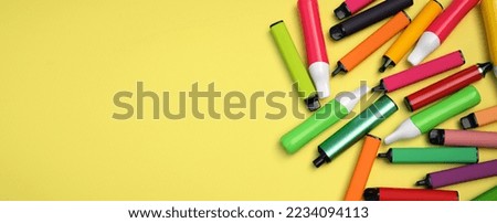 Set of multicolor disposable electronic cigarettes on a bright yellow background. The concept of modern smoking, vaping and nicotine.