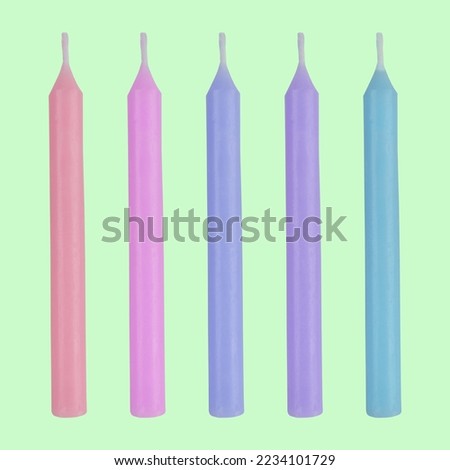 Five colorful pastel vivid color candles on bright green background