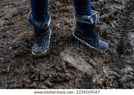 Child's feet in dirty stained boots, muddy background. Dirty in the mud warm boots. Hight quality photo
