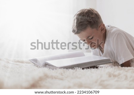 A little boy looks at a photo album on the bed in the room
