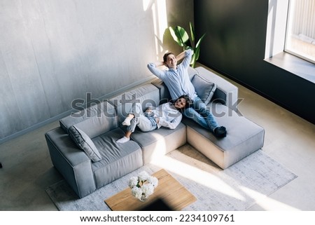 Loving couple holding hands, relaxing on cozy sofa in modern living room top view, happy beautiful woman and man resting on comfortable couch together, spending lazy weekend, enjoying leisure time Royalty-Free Stock Photo #2234109761