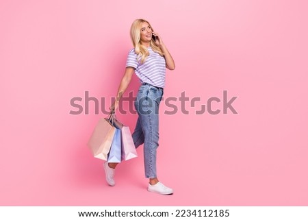 Full size profile photo of attractive charming girl walking hold bags speak telephone isolated on pink color background