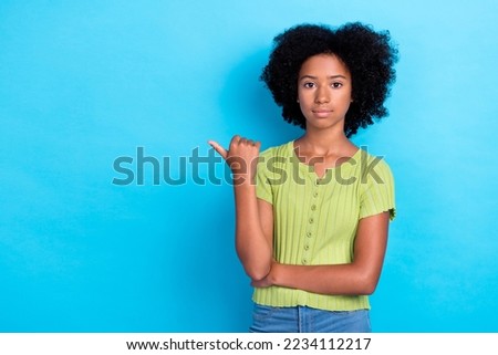 Photo of serious confident girl with perming hair dressed green t-shirt directing empty space sale isolated on blue color background