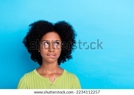 Photo of intelligent thoughtful positive girl with perming coiffure wear green t-shirt look empty space isolated on blue color background