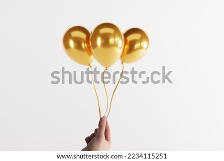 Hand holds gold balloons on a light background. Concept for the release of balloons, balloons inflated with air. Royalty-Free Stock Photo #2234115251