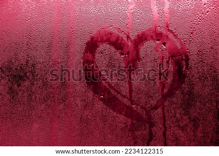 Heart painted on misted glass. Valentines day, love symbol on frozen glass in winter. Selective focus. Color of the year 2023 - Viva Magenta Royalty-Free Stock Photo #2234122315