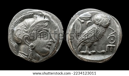 Ancient Greek coin showing goddess Athena face and owl. Old rare money of Athens, vintage silver tetradrachm isolated on black background, macro. Theme of Greece, retro, animal, culture and history.