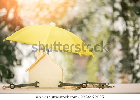 The yellow umbrella for protect to home and wrench with repairing and construction tools put on the wood in the public park, Saving money and loan for renovation to real estate and house concept.