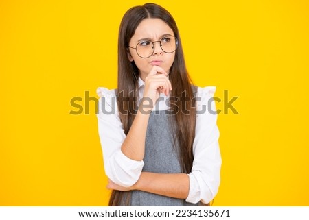 Thinking teenager girl, thoughtful emotion. Smart nerdy school girl touching cheek and thinking against yellow background. Child think and idea concept.