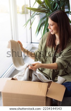 Woman excited to look trough her online order on winter clothes