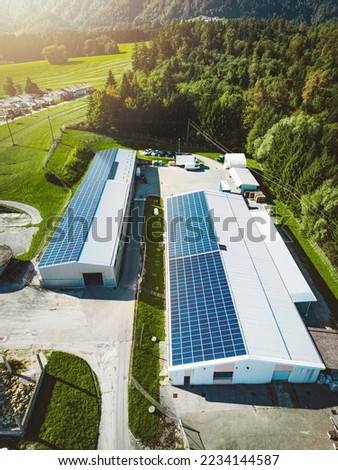 Vertical photo of two industrial buildings with a roof covered in solar panels - renewable energy 