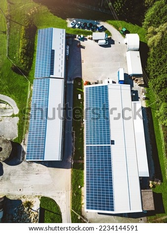 Vertical photo top down aerial view solar panels on the roof of two warehouses in the countryside