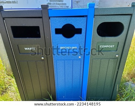 A closeup of trash cans setup to sort garbage into the proper bins. They are three different colors and labeled for waste, recycling, and compost.