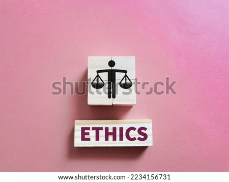 Business ethics concept on wooden cubes against pink background.