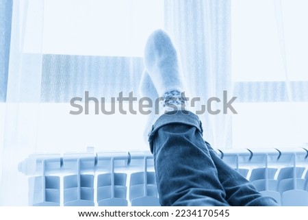 Woman wearing woolen socks with feet on heater