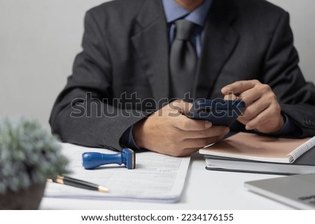 businessman using smartphone and working on documents at office, man holding phone reading bank receipt taxes money finances, loan expenses or job paperwork.