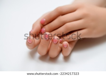 Closeup top view of elegant pastel pink natural manicure. Female hands isolated on white background. Horizontal color photography.