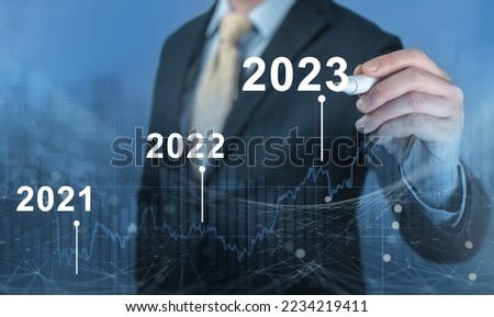 Economy recovery after falling due to inflation, stagnation, recession, 2023 financial chart. Businessman pointing graph of future growth on blue digital screen Royalty-Free Stock Photo #2234219411