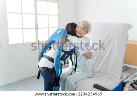 A caregiver wearing a power assist suit and assisting the elderly. Royalty-Free Stock Photo #2234234969