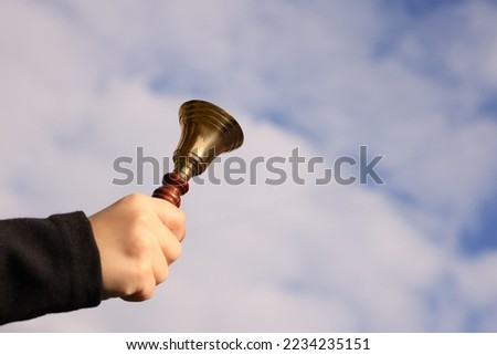 Pupil with school bell against cloudy sky, closeup. Space for text
