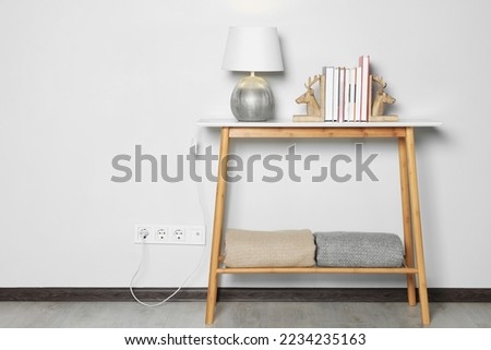 Lamp with books on wooden table near white wall, space for text Royalty-Free Stock Photo #2234235163