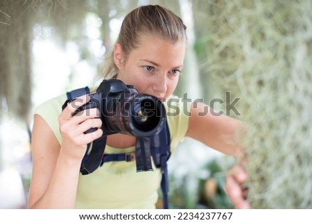 young woman taking photos in the forest with a camera