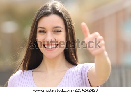 Happy teen gestures thumb up standing in the street