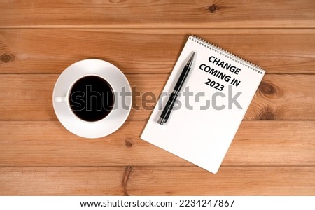 a cup of coffee and a notepad with pens on a wooden background