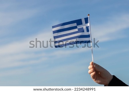 Greek flag in hand flutters in the wind against the sky, independence national day of Greece, country freedom, patriotism, Public Holiday, patriotic festival