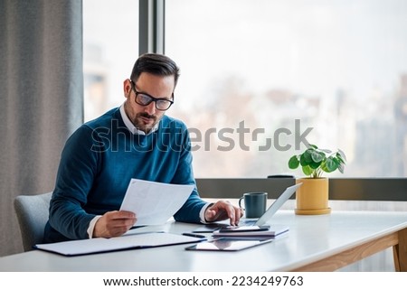 Busy elegant bearded adult company director, checking the company finances, at the office. Royalty-Free Stock Photo #2234249763
