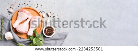Banner with copy space - raw chicken legs on wooden plate with seasonings over gray concrete background. Chicken drumsticks ready to cook. Dietary meat, healthy eating concept Royalty-Free Stock Photo #2234253501