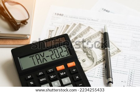 Tax 2023. Word Tax 2023 on calculator. Business and tax concept .Calculator, currency, dollar bills close up. Income Statement. paying the tax rate. Taxation, taxes burden. Business concept.

