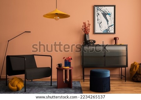 Interior design of cozy living room with mock up poster frame, glass sideboard, yellow lamp, navy pouf, carpet, black armchair, vase with dried flowers and personal accessories. Home decor. Template. Royalty-Free Stock Photo #2234265137