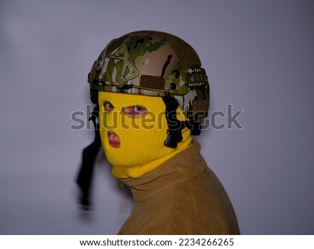 A man in a yellow balaclava and a military helmet. Isolated on gray background
