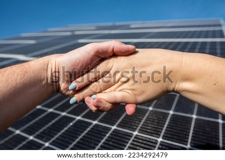 Handshake in front of solar energy photovoltaic panels outdoors. concept of agreement before installing solar panels