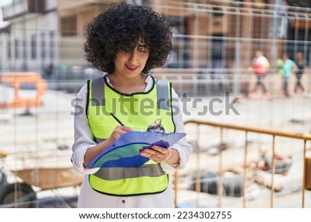 Young middle east woman architect writing report at street