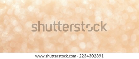Blurred beige background with circle sparkling lights. Shiny coral glittery bokeh of christmas garland. Holiday backdrop