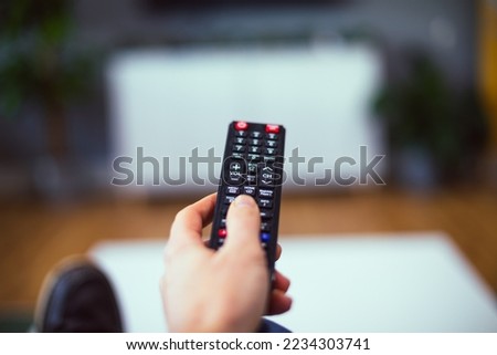 A TV remote control, resting on a table in a lounge. Clear shot of the control, in a nicely lit environment. Good depth of field and clarity.