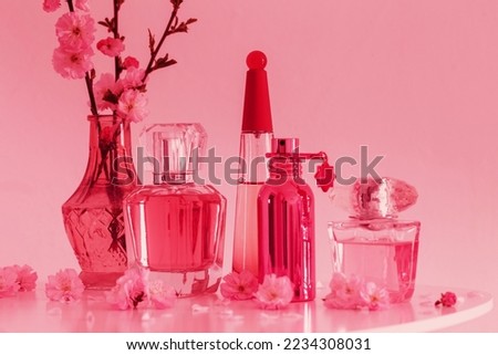 branches of blossoming almonds in  vase and bottle of perfumes in trendy color of year 2023 