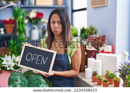 Hispanic young woman working at florist with open sign depressed and worry for distress, crying angry and afraid. sad expression. 
