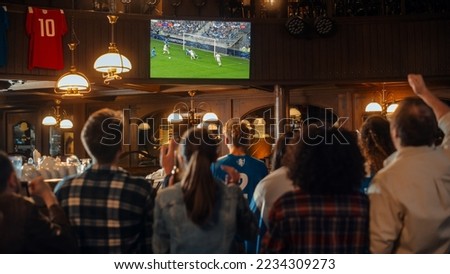 Group of Friends Watching a Live Soccer Match on TV in a Sports Bar. Excited Fans Cheering and Shouting. Young People Celebrating When Team Scores a Goal and Wins the Football World Cup. Royalty-Free Stock Photo #2234309273