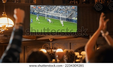 Group of Friends Watching a Live Soccer Match on TV in a Sports Bar. Excited Fans Cheering and Shouting. Young People Celebrating When Team Scores a Goal and Wins the Football World Cup. Royalty-Free Stock Photo #2234309281