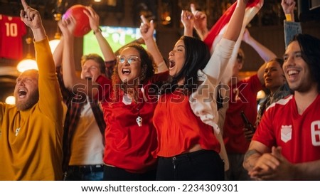 Group of Soccer Fans in Red Clothes Cheering, Screaming, Raising Hands and Jumping During a Football Game Live Broadcast in a Sports Pub. Player Scores a Goal and Friends Celebrate. Slow Motion. Royalty-Free Stock Photo #2234309301