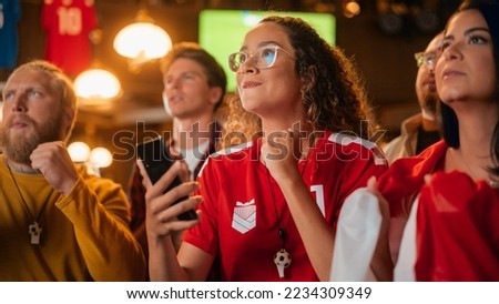 Portrait of an Anxious Multiethnic Female in Red Jersey Holding a Smartphone, Nervous About the Sports Bet on Her Favorite Soccer Team. Happy Victorious Emotions When Football Team Scores a Goal. Royalty-Free Stock Photo #2234309349