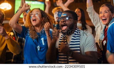 Group of Multiethnic Friends Watching a Live Soccer Match on TV in a Sports Bar. Fans with Painted Faces Cheering. Young People Celebrating When Team Scores a Goal and Wins the Football World Cup. Royalty-Free Stock Photo #2234309501