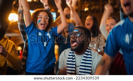 Group of Multiethnic Friends Watching a Live Soccer Match on TV in a Sports Bar. Fans with Painted Faces Cheering. Young People Celebrating When Team Scores a Goal and Wins the Football World Cup. Royalty-Free Stock Photo #2234309539