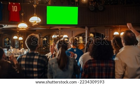 Group of Multicultural Friends Watching a Live Sports Match on TV with Green Screen Display in a Bar. Happy Fans Cheering and Shouting, Celebrating When Team Scores a Goal and Wins the Tournament. Royalty-Free Stock Photo #2234309593